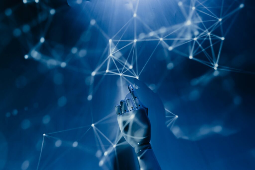 A robotic hand reaching into a digital network on a blue background, symbolizing AI technology.
